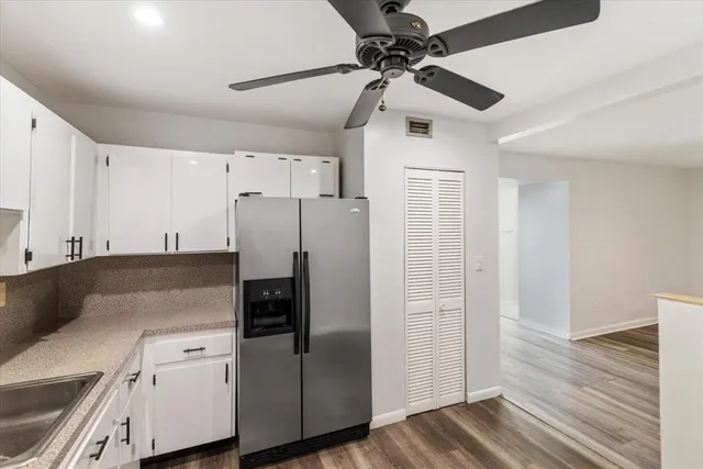 a kitchen with stainless steel appliances a refrigerator a sink and white cabinets