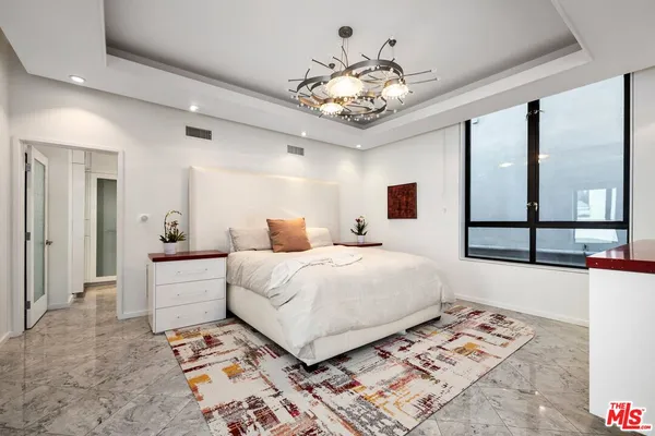 a bedroom with a large bed and a chandelier