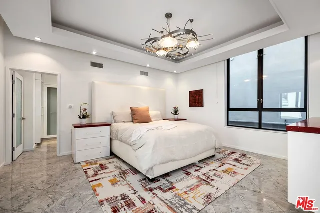 a bedroom with a large bed and a chandelier