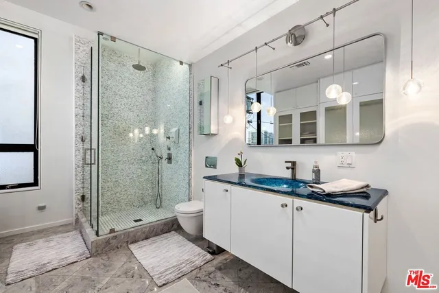 a bathroom with a granite countertop sink mirror and toilet