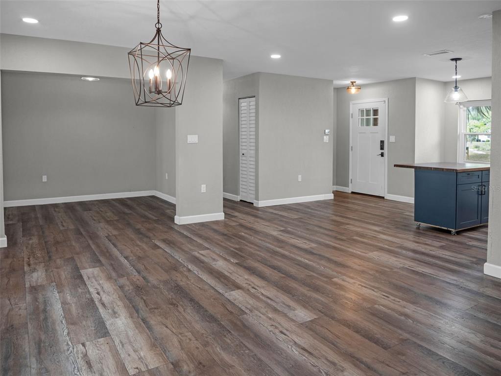 628 Bethel Street Keystone Heights, FL 32656 - Photo 10 of 49 an empty room with wooden floor and kitchen view