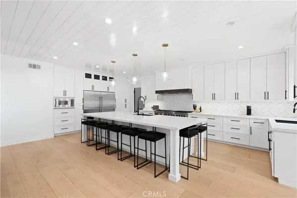 a kitchen with stainless steel appliances kitchen island granite countertop a table chairs sink and cabinets