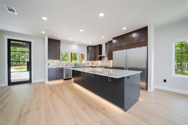 a large kitchen with stainless steel appliances kitchen island a large counter top and a wooden floors