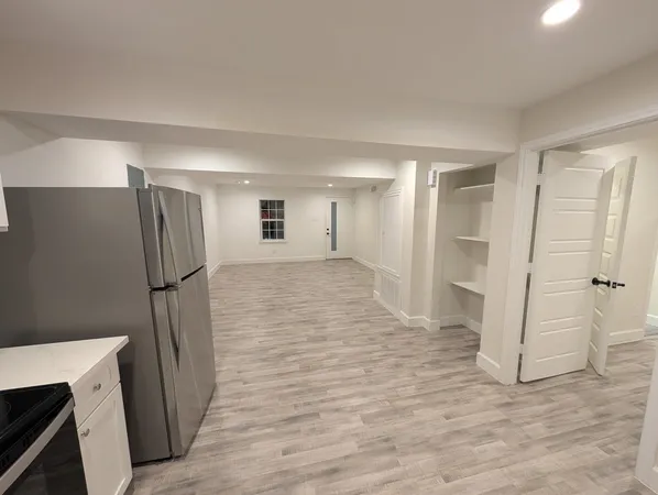 a view of an empty room with wooden floor and a ceiling fan