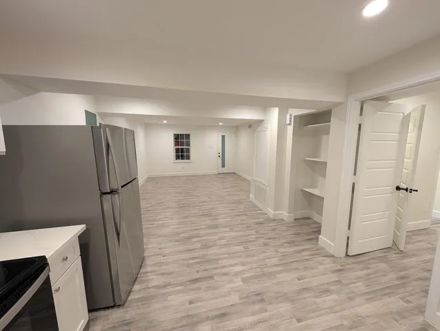a view of an empty room with wooden floor and a ceiling fan