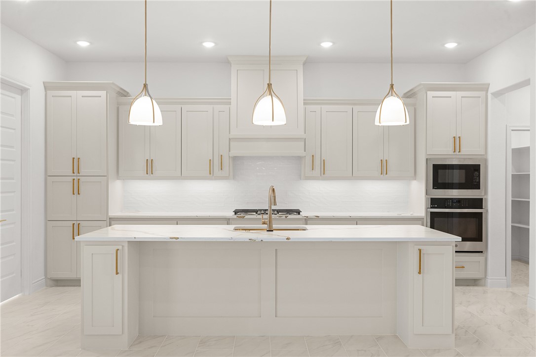 6512 Agave Court Bryan, TX 77808 - Photo 18 of 42 Kitchen featuring light marble finish flooring, backsplash, stainless steel oven, light stone countertops, and built in microwave
