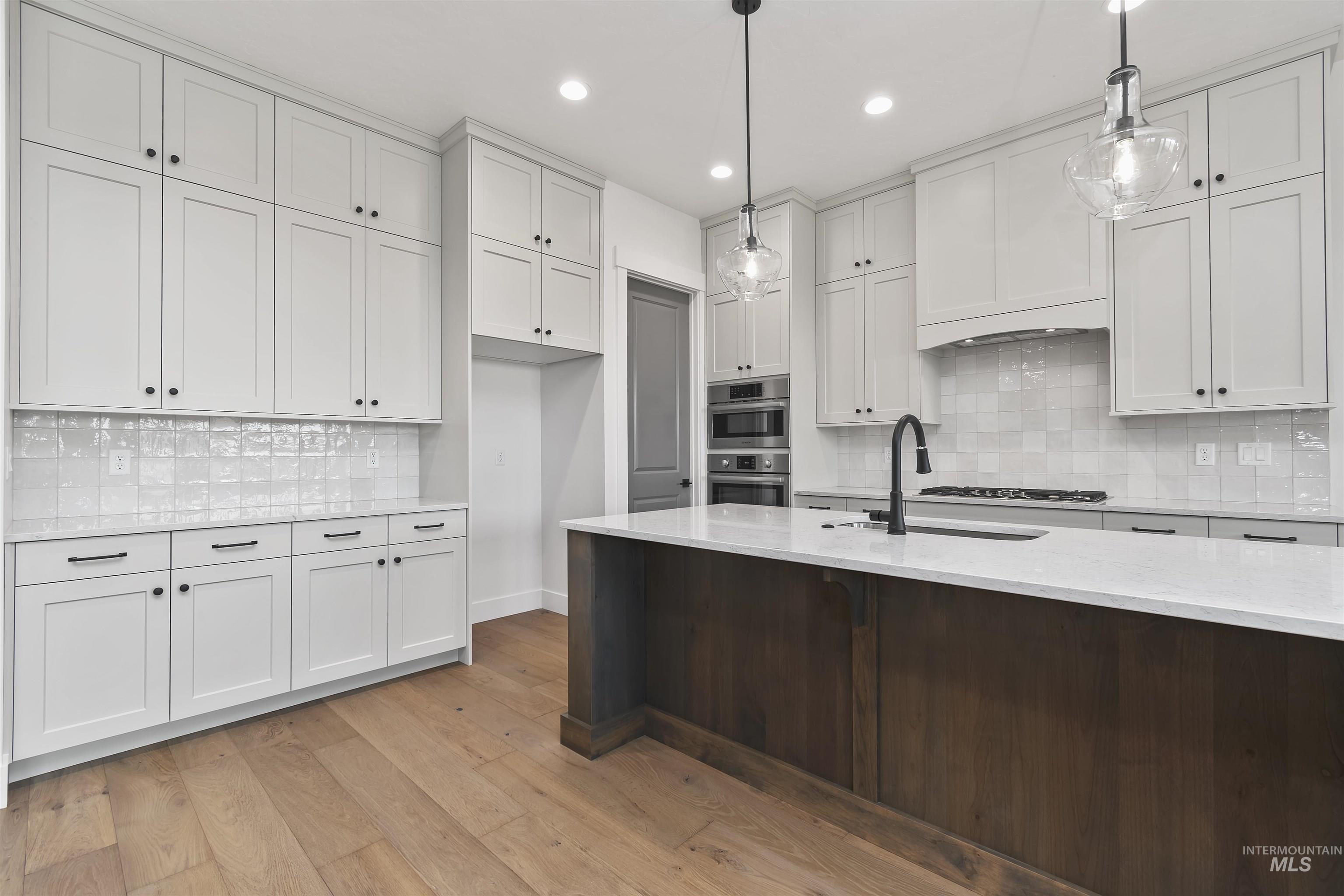 3875 South Corabell Avenue Meridian, ID 83642 - Photo 10 of 27 Kitchen with tasteful backsplash, light stone counters, white cabinets, light wood-style flooring, and stainless steel appliances