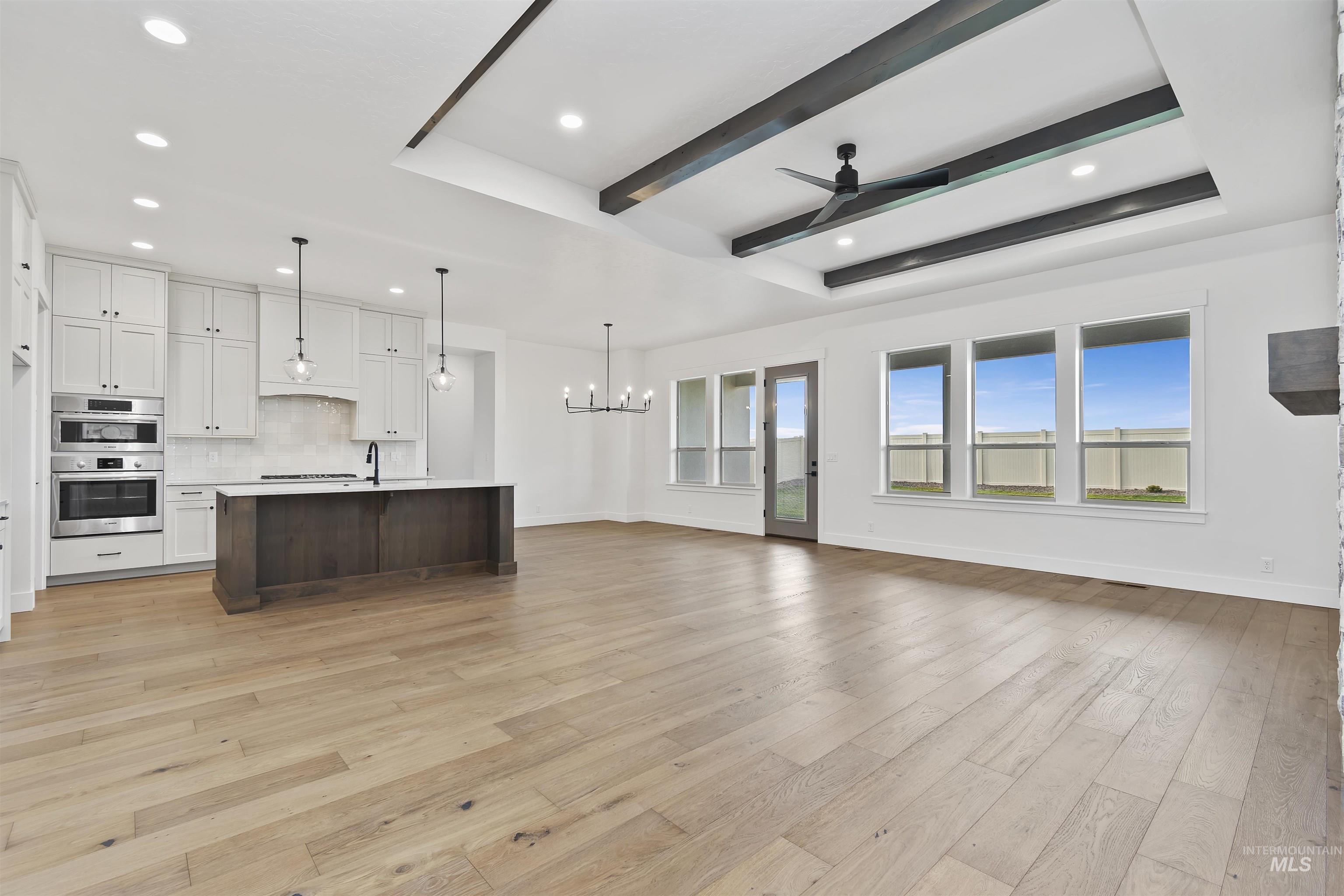 3875 South Corabell Avenue Meridian, ID 83642 - Photo 12 of 27 Unfurnished living room with a chandelier, a ceiling fan, recessed lighting, light wood finished floors, and beamed ceiling