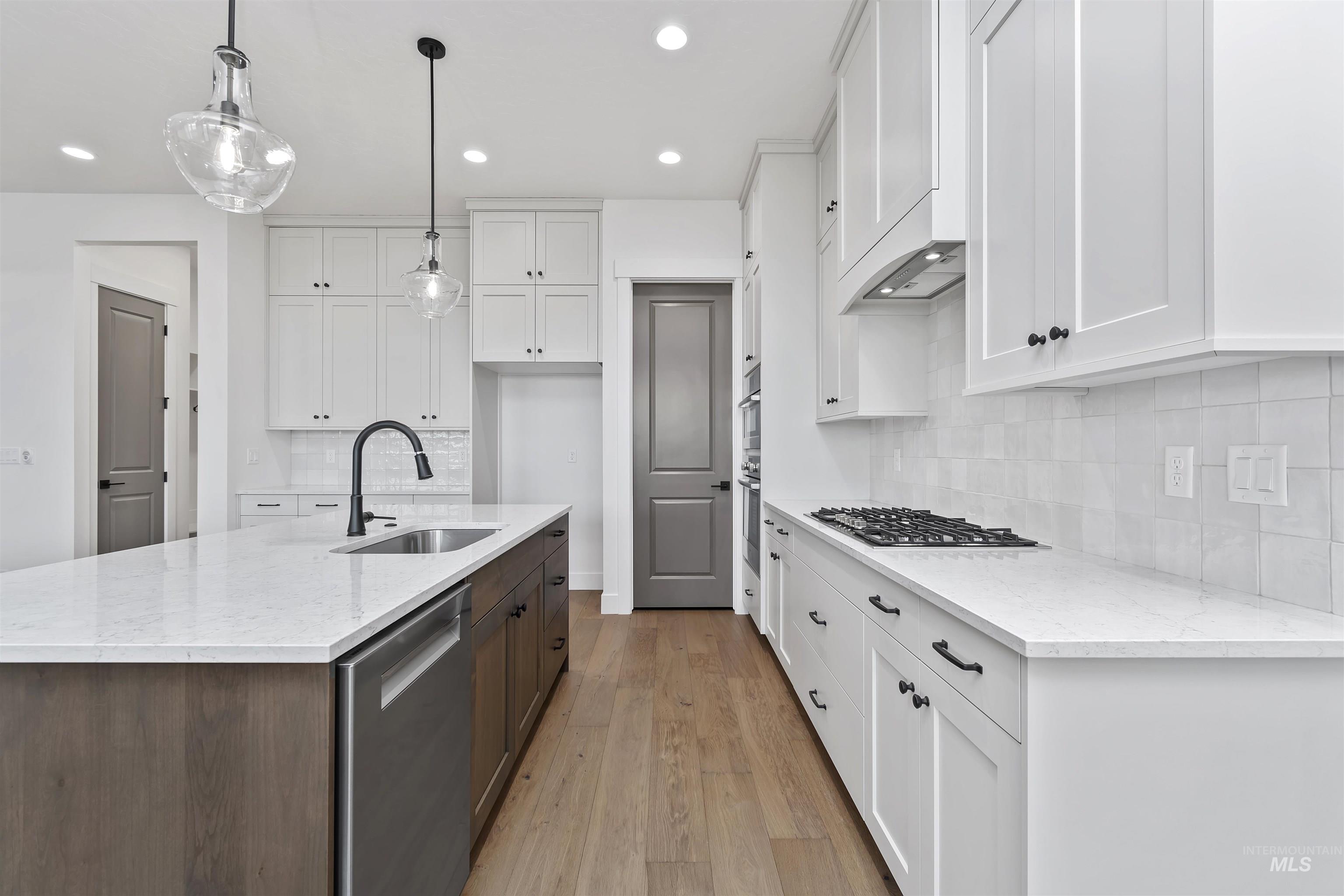 3875 South Corabell Avenue Meridian, ID 83642 - Photo 7 of 27 Kitchen with white cabinets, light stone countertops, stainless steel appliances, an island with sink, and recessed lighting