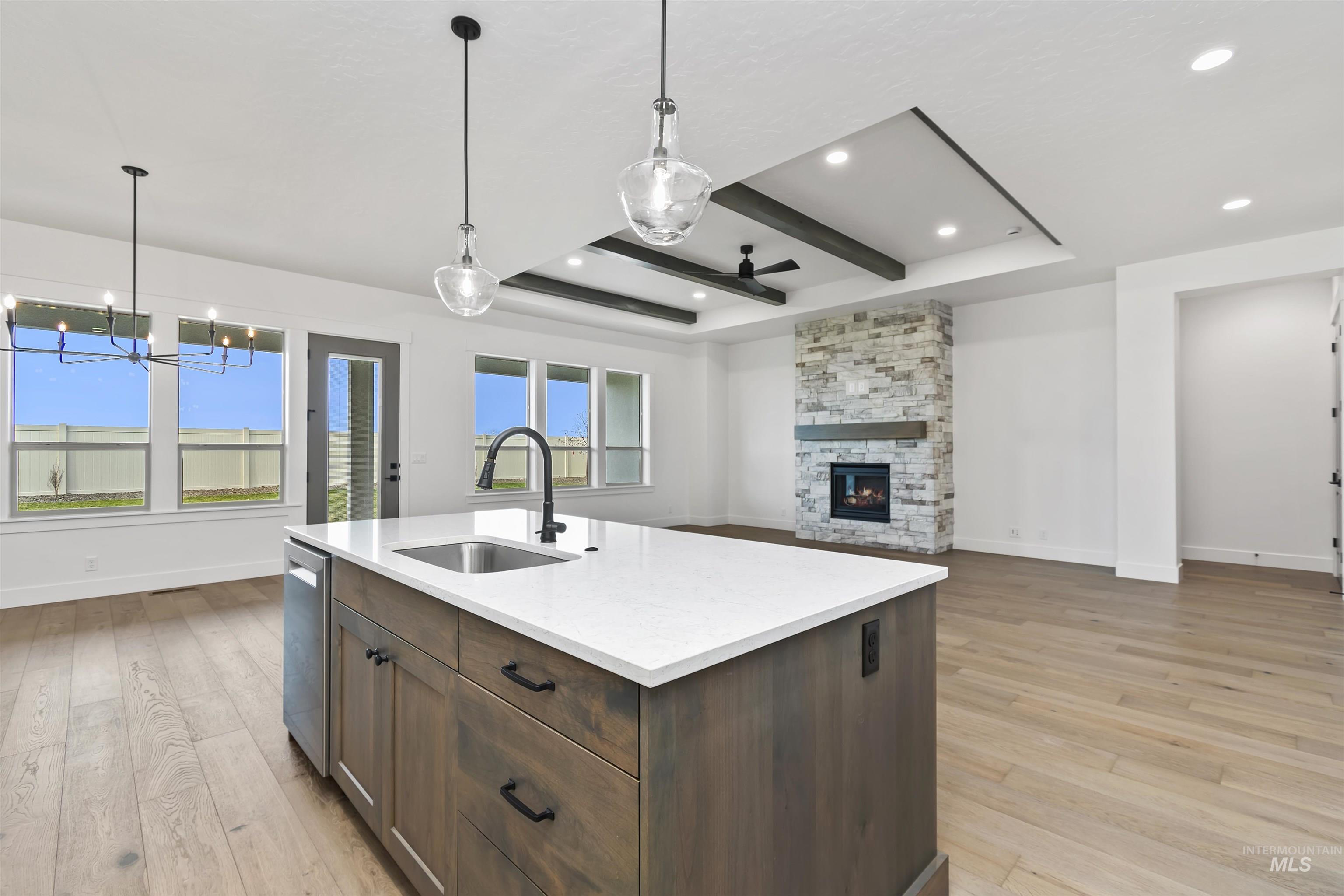 3875 South Corabell Avenue Meridian, ID 83642 - Photo 25 of 27 Kitchen featuring pendant lighting, dark brown cabinetry, a fireplace, open floor plan, and light wood-type flooring