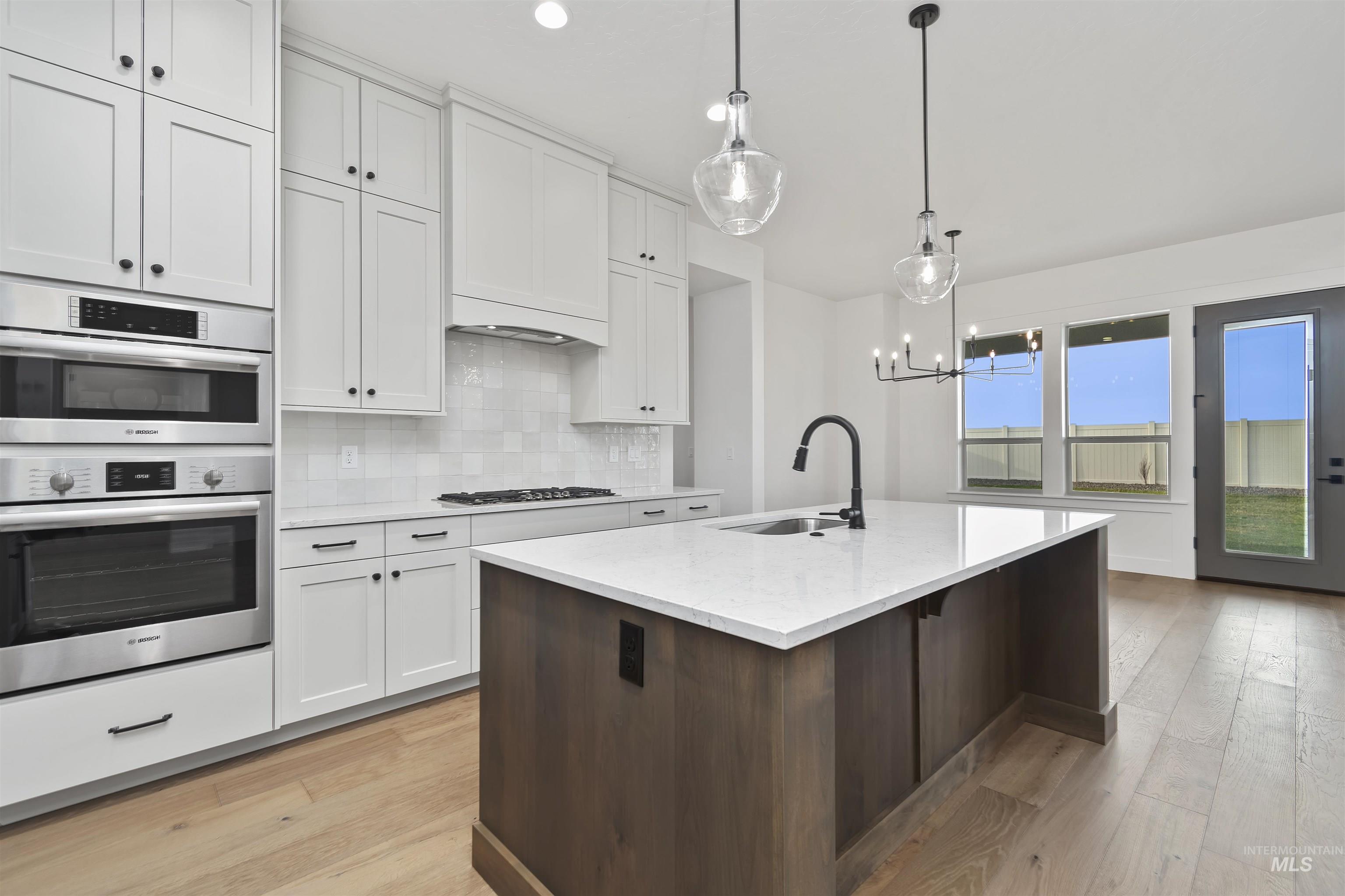 3875 South Corabell Avenue Meridian, ID 83642 - Photo 9 of 27 Kitchen with white cabinetry, stainless steel appliances, tasteful backsplash, and hanging light fixtures