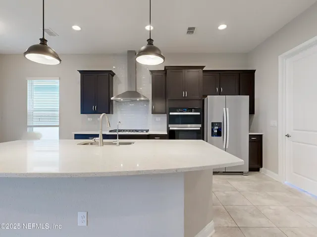 a large kitchen with stainless steel appliances a refrigerator sink and microwave