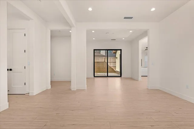 a view of an empty room with glass door and a bathroom