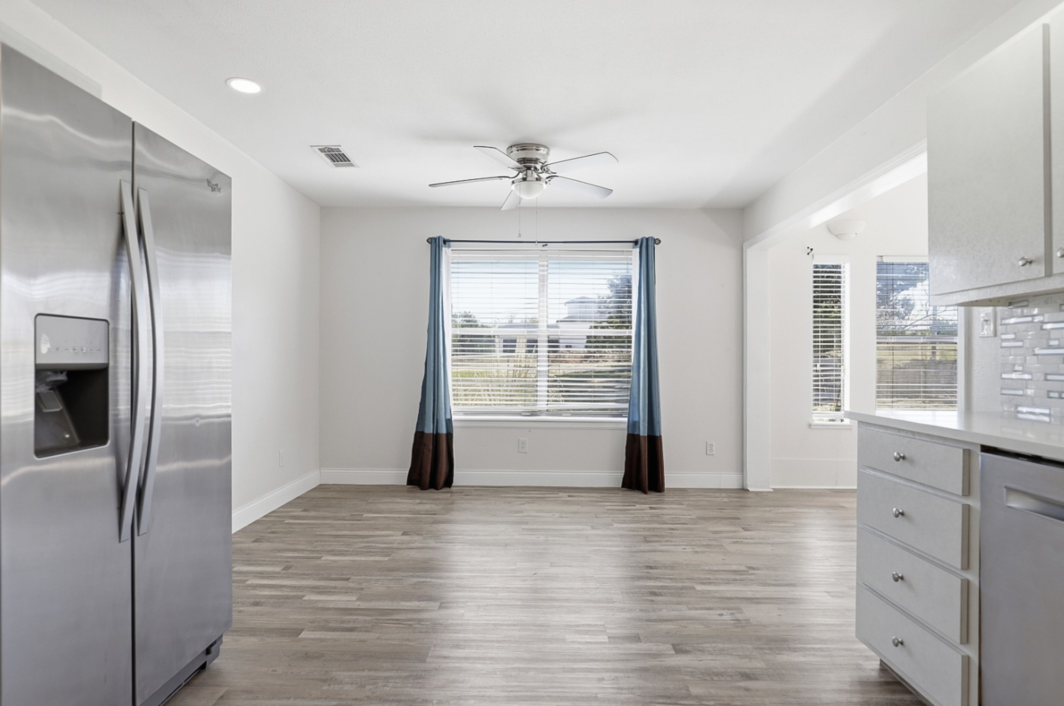 128 Skyview Terrace Leander, TX 78641 - Photo 6 of 23 Eat-in area off the kitchen with ceiling fan. The kitchen featuring stainless steel appliances, light wood-type flooring, recessed lighting, and white cabinets