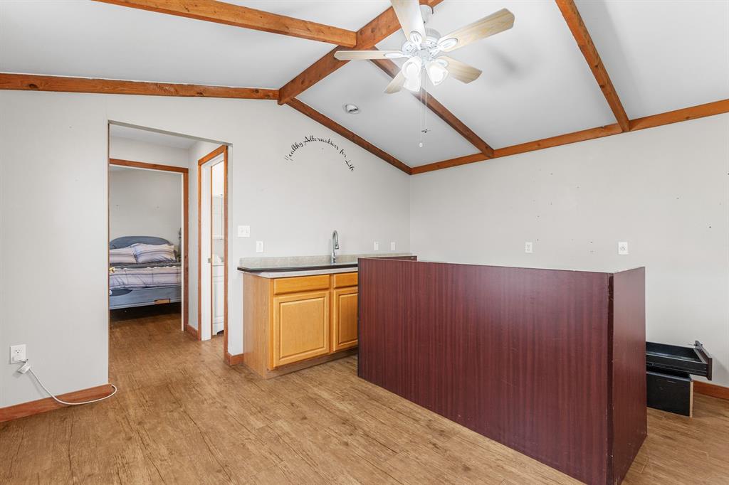 13315 Highway 281 Scotland, TX 76379 - Photo 36 of 40 Vaulted ceiling with exposed wood beams, ceiling fan and hallway to bathroom and bedroom
