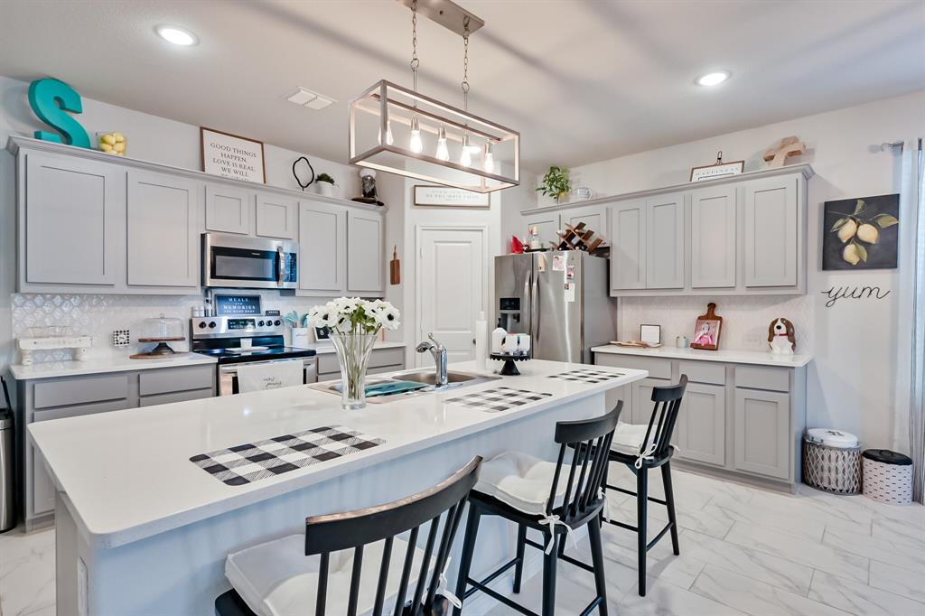 10621 Alpine Meadow Lane Fort Worth, TX 76140 - Photo 14 of 35 a kitchen with stainless steel appliances kitchen island granite countertop a table chairs microwave and sink