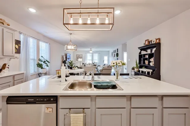 a living room with couches a table and chairs with potted plants