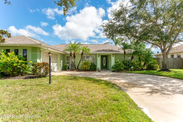a view of a house with potted plants and a large tree