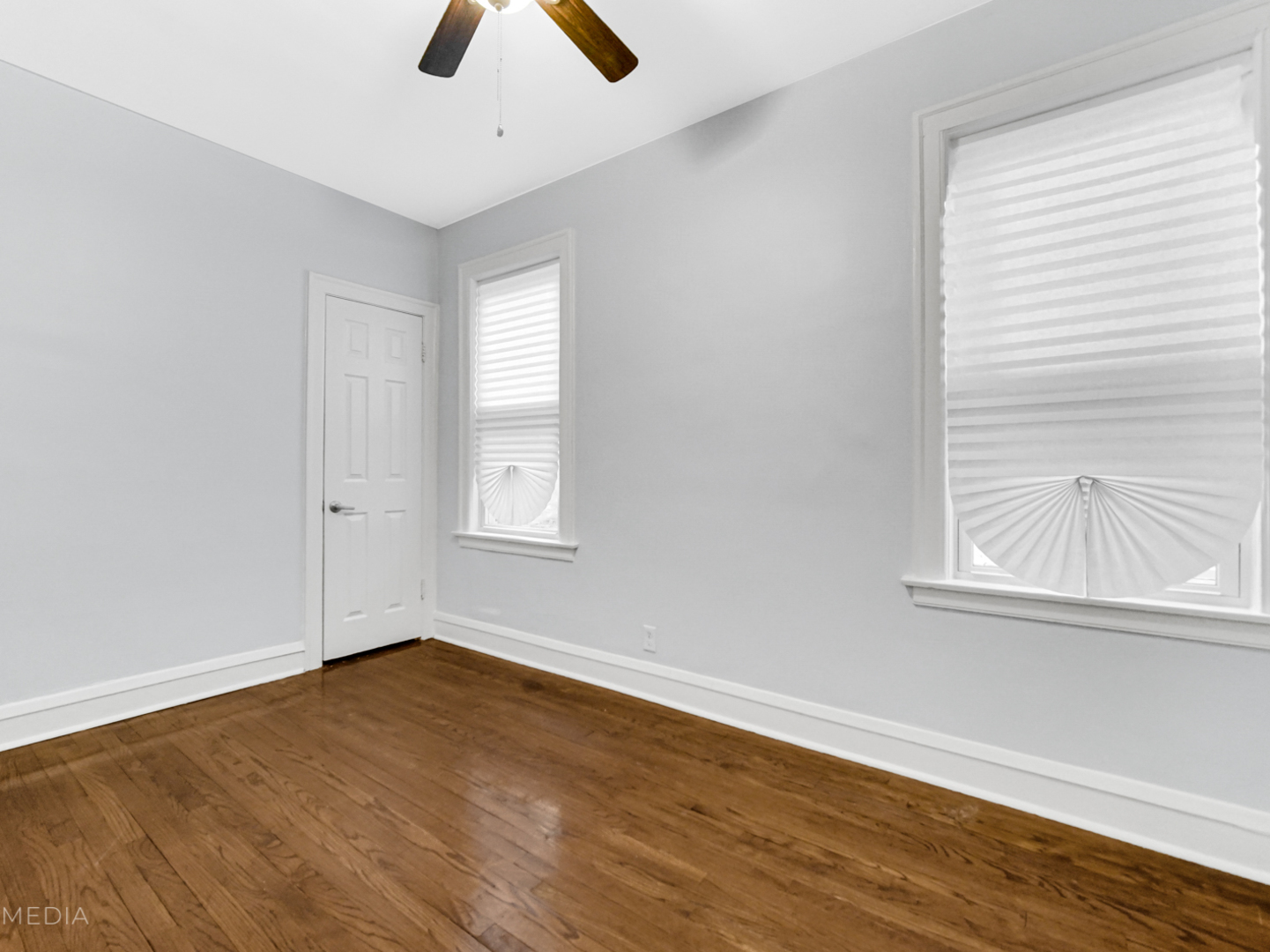 8553 South Sangamon Street Chicago, IL 60620 - Photo 5 of 27 an empty room with wooden floor chandelier fan and windows