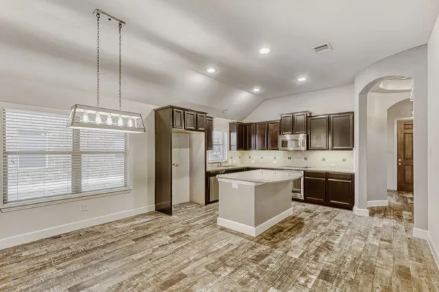 a large kitchen with a refrigerator a sink dishwasher a stove and a refrigerator with wooden floor