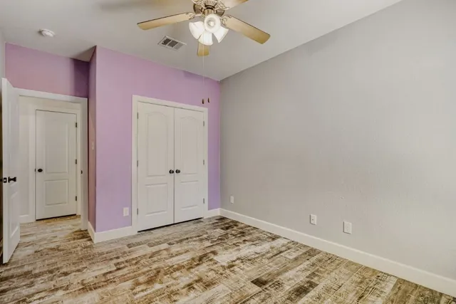 a view of a livingroom with a chandelier fan and wooden floor