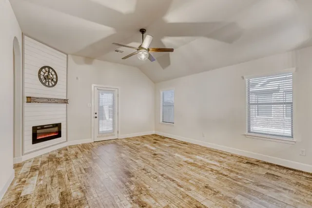 a view of empty room with wooden floor and fan
