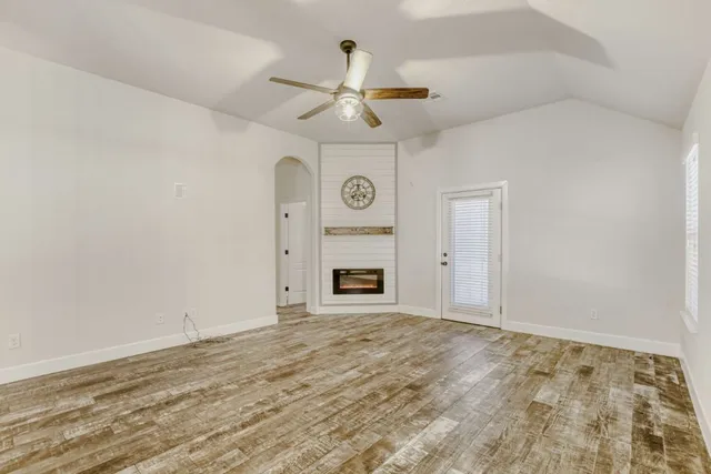 a view of an empty room with a fireplace and a ceiling fan