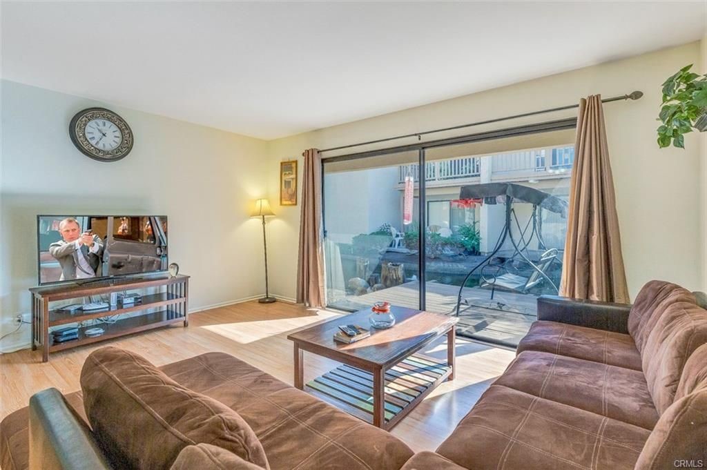 424 Orange Blossom, Unit 204 Irvine, CA 92618 - Photo 3 of 6 a living room with furniture a flat screen tv and a floor to ceiling window