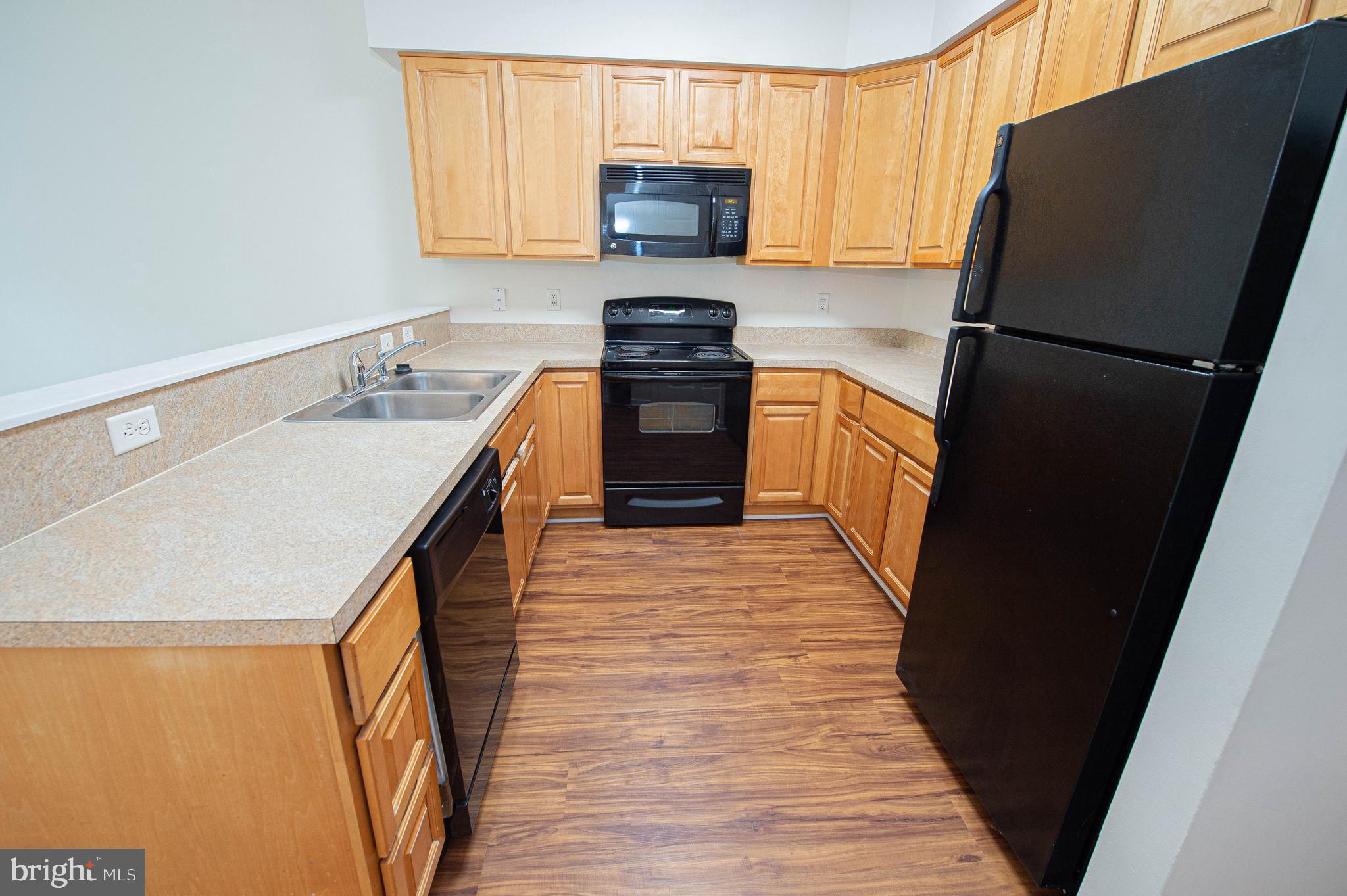 420 Parkview Court, Unit F Salisbury, MD 21804 - Photo 23 of 87 a kitchen with a refrigerator a stove top oven a sink and dishwasher with wooden floor