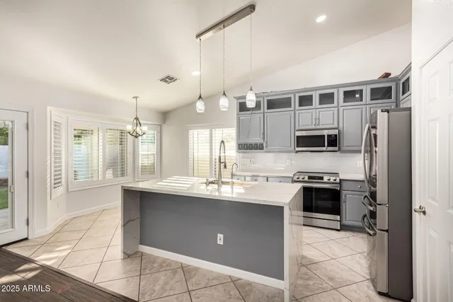 a kitchen with stainless steel appliances granite countertop a sink a stove a refrigerator and cabinets