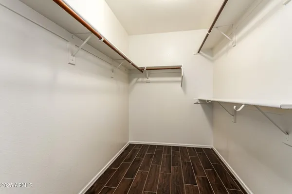an empty room with wooden floor chandelier fan and windows
