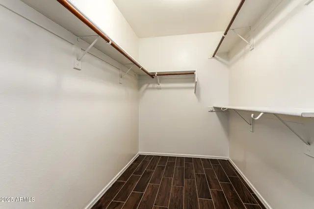 an empty room with wooden floor chandelier fan and windows