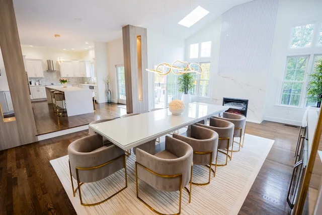 a kitchen with stainless steel appliances kitchen island granite countertop a dining table chairs and a refrigerator