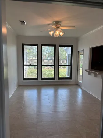 an empty room with chandelier fan and windows