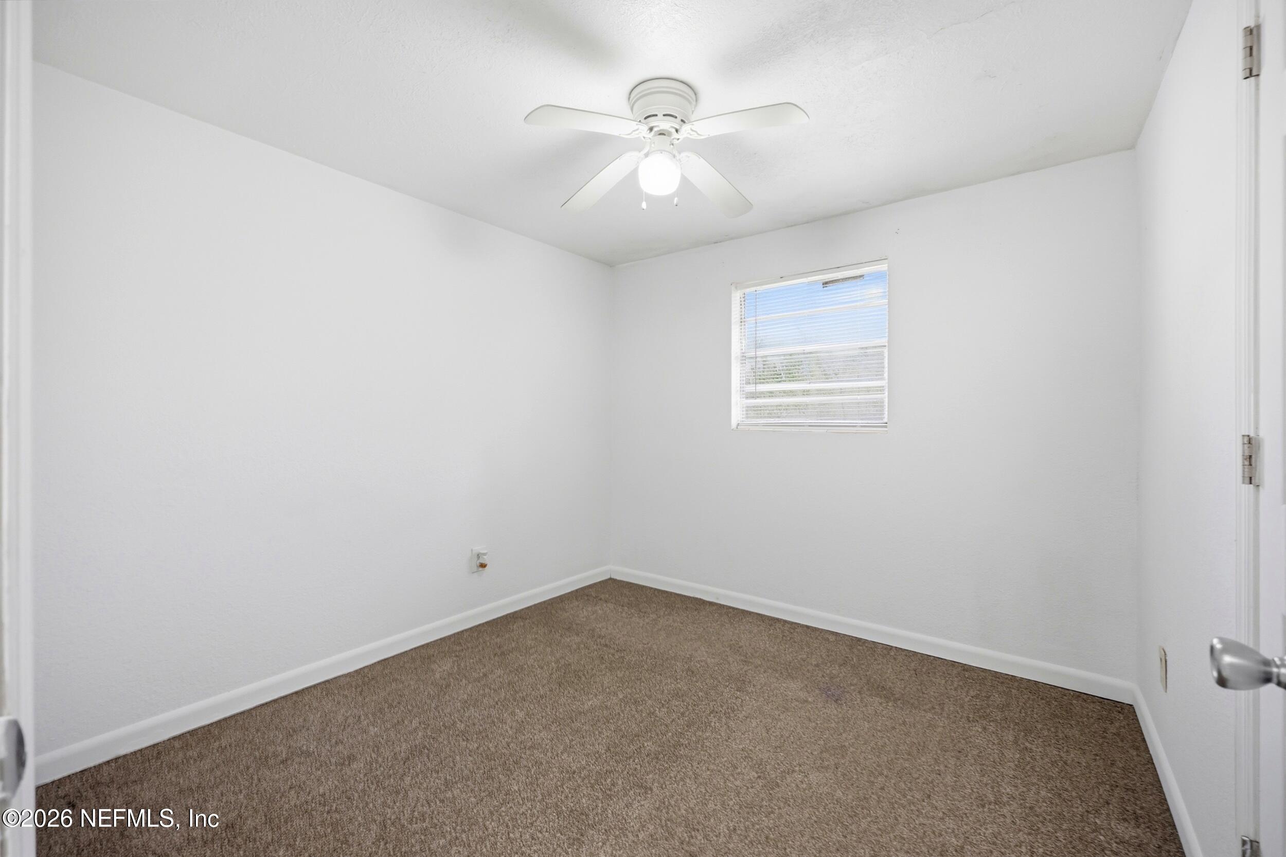 9843 Wagner Road Jacksonville, FL 32219 - Photo 14 of 40 an empty room with a chandelier fan and windows