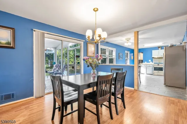 a dining room with wooden floor a chandelier a wooden table and chairs