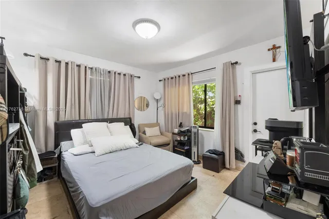 a bedroom with a bed a flat screen tv and a large window