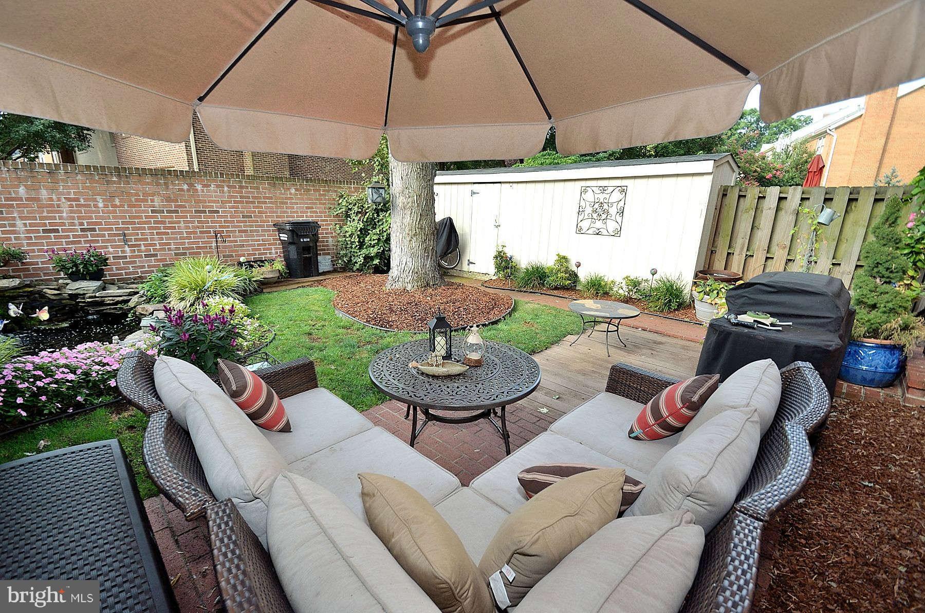 8521 Forrester Boulevard Springfield, VA 22152 - Photo 26 of 28 a view of a patio with couches table and chairs under an umbrella