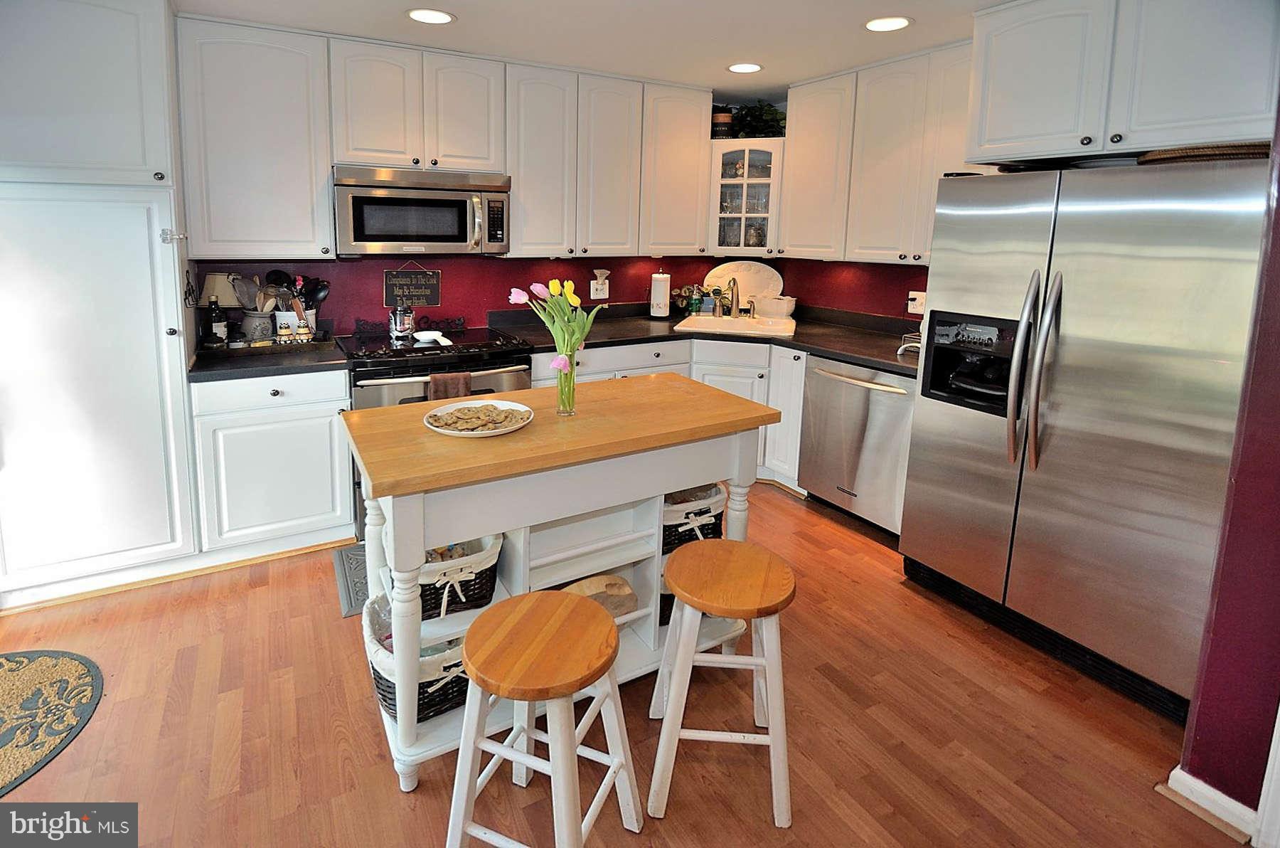 8521 Forrester Boulevard Springfield, VA 22152 - Photo 5 of 28 a kitchen with stainless steel appliances wooden floor dining table and chairs