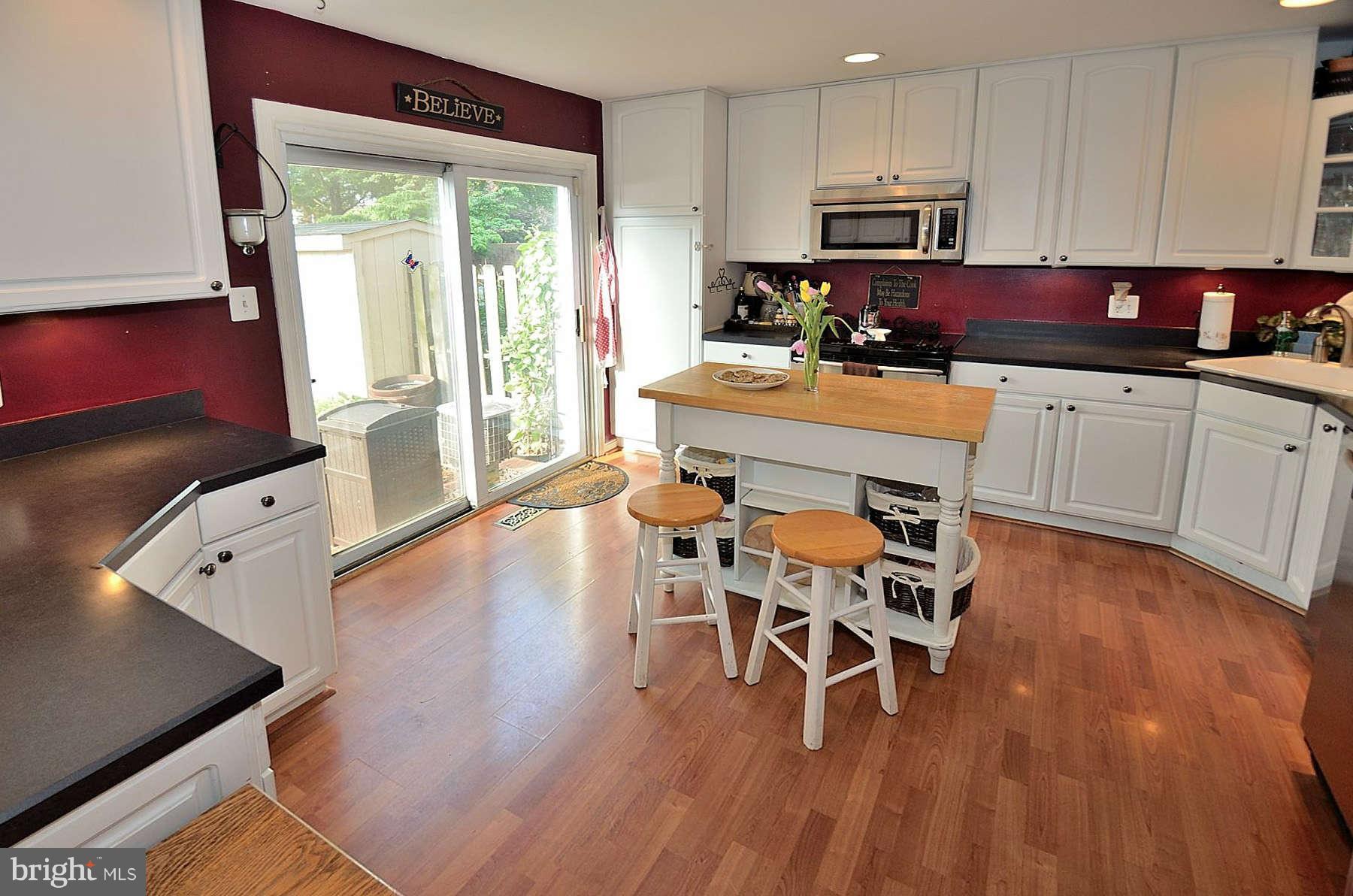 8521 Forrester Boulevard Springfield, VA 22152 - Photo 6 of 28 a kitchen with stainless steel appliances granite countertop a stove top oven a dining table and chairs with wooden floor