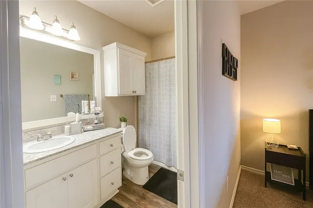 a bathroom with a granite countertop sink toilet a mirror and a shower