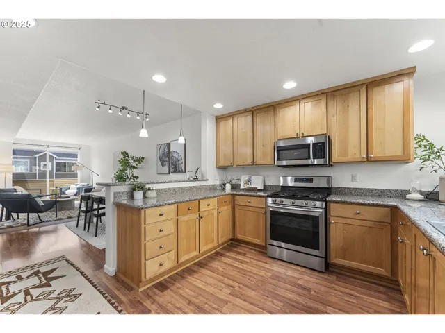 a kitchen with stainless steel appliances granite countertop a stove top oven a sink dishwasher a dining table and chairs