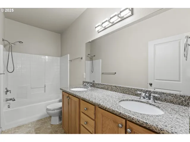a bathroom with a granite countertop sink double mirror bathtub shower and a toilet