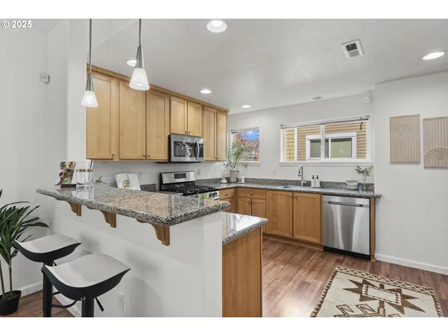 a kitchen with stainless steel appliances granite countertop a sink a stove a refrigerator cabinets and living room view