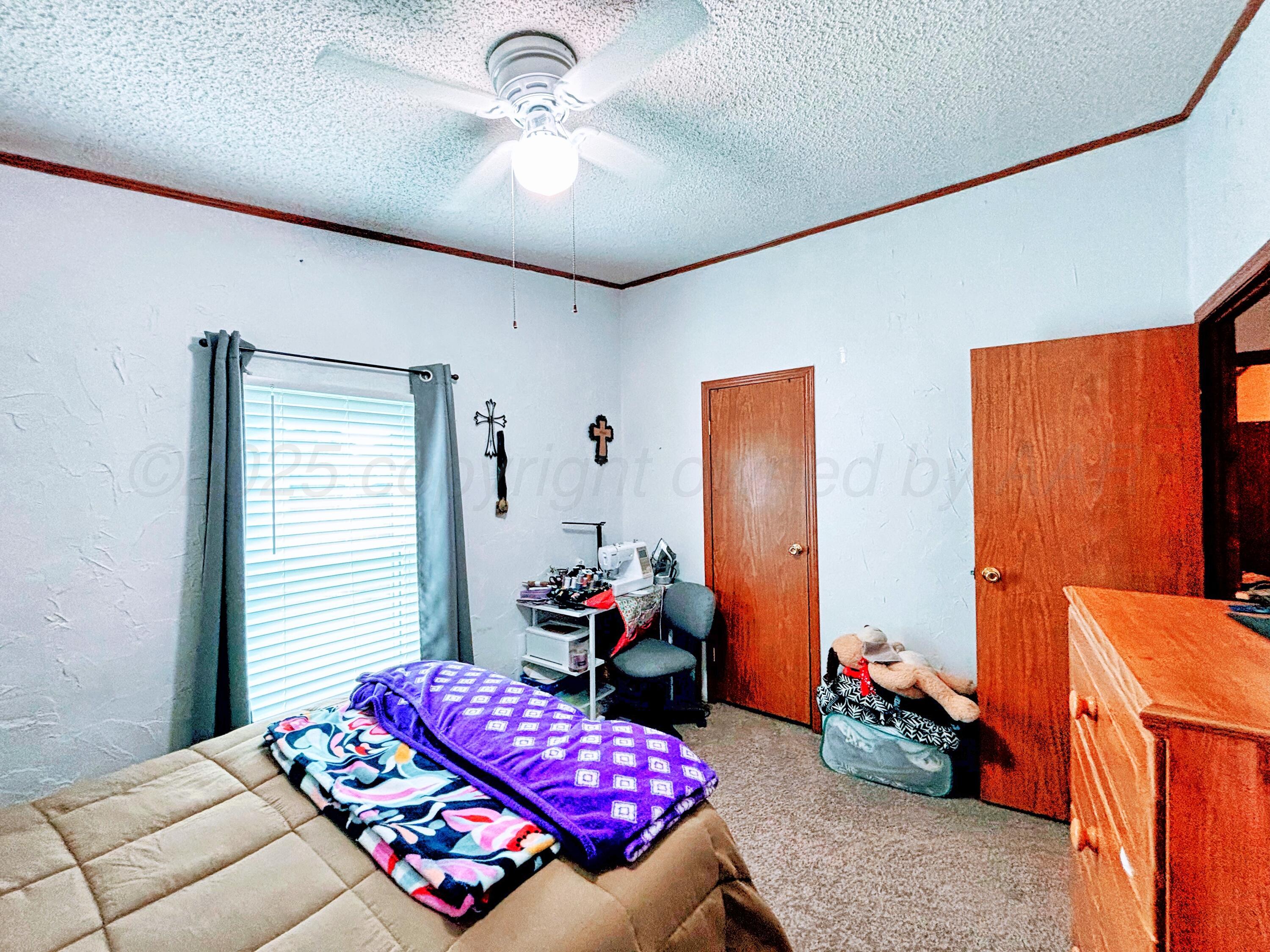 1010 South Baylor Street Perryton, TX 79070 - Photo 25 of 35 a bedroom with a bed and a chandelier