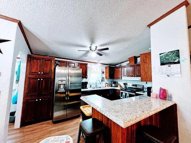 a kitchen with stainless steel appliances granite countertop a sink refrigerator and cabinets