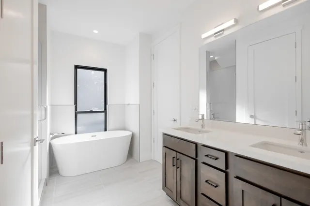a bathroom with a double vanity sink mirror and bathtub