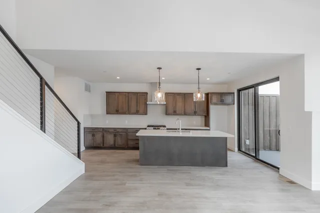 a large kitchen with stainless steel appliances a large counter top and a refrigerator