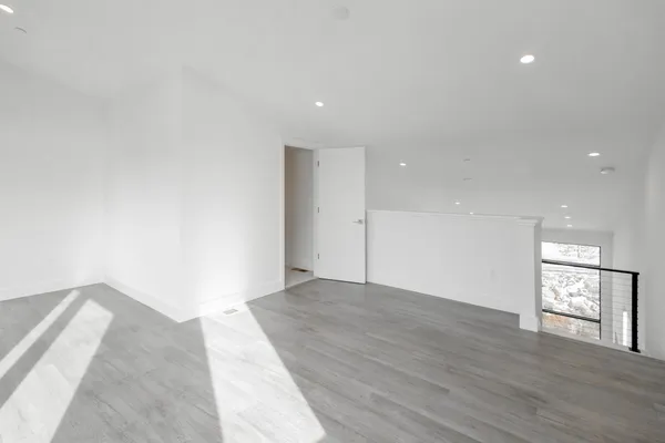a view of an empty room with wooden floor and a window