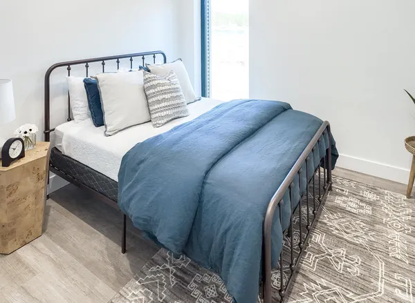 a bed sitting in a bedroom next to a window with lamp